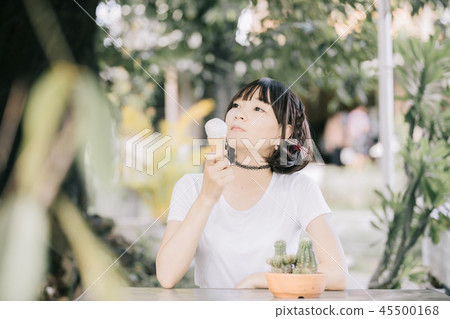portrait of asian girl with white shirt and skirt eating ice cream in outdoor nature vintage film style 45500168