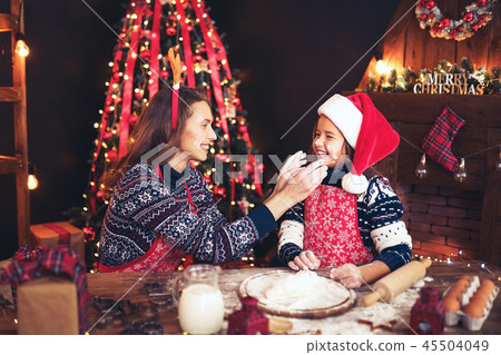 Merry Christmas and Happy Holidays. Mother and daughter cooking Christmas cookies. 45504049