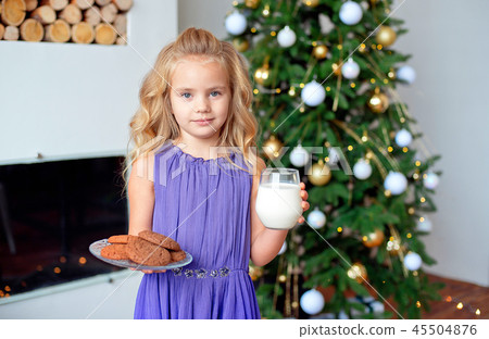 A little girl with blond hair prepared treats for Sanda. Christmas background, new year concept A little girl with blond hair prepared treats for Sanda. Christmas background, new year concept 45504876