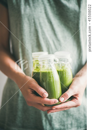 Female in dress holding bottles of green smoothie or juice Female in dress holding bottles of green smoothie or juice 45508022