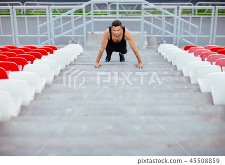 Serious man doing pushups on stadium stairs 45508859