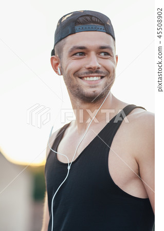 Smiling man in headphones listening to music outdoors Smiling man in headphones listening to music outdoors 45508902