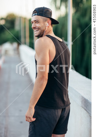 Smiling man in headphones listening to music outdoors Smiling man in headphones listening to music outdoors 45508903
