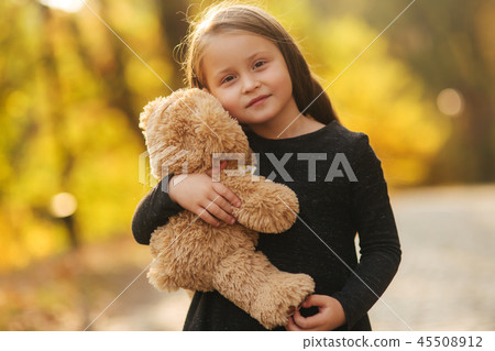 Portrait of little girl which hold teddy bear in hands. Happy child in the park. Beautiful girl Portrait of little girl which hold teddy bear in hands. Happy child in the park. Beautiful girl 45508912