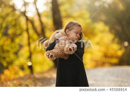 Portrait of little girl which hold teddy bear in hands. Happy child in the park. Beautiful girl 45508914
