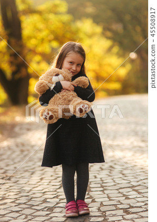 Portrait of little girl which hold teddy bear in hands. Happy child in the park. Beautiful girl 45508917