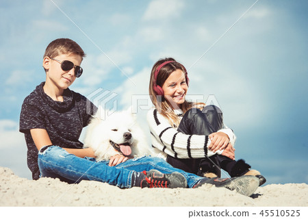 Happy 11 year old boy hugging his dog breed Samoyed at the seashore against a blue sky close up Happy 11 year old boy hugging his dog breed Samoyed at the seashore against a blue sky close up 45510525