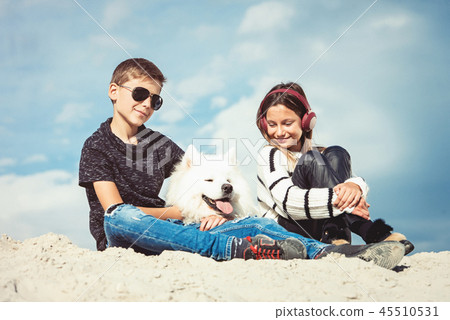 Happy 11 year old boy hugging his dog breed Samoyed at the seashore against a blue sky close up Happy 11 year old boy hugging his dog breed Samoyed at the seashore against a blue sky close up 45510531