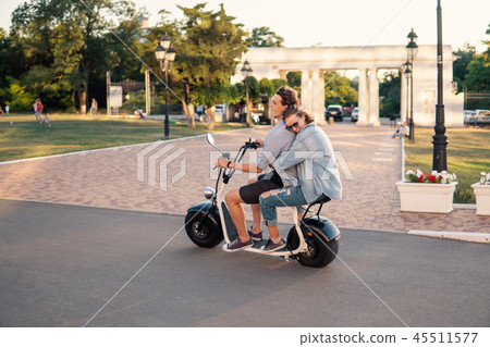 Lovely young happy couple driving electric bike Lovely young happy couple driving electric bike 45511577