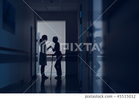 Lady is leaning on doctor and cane in hallway Lady is leaning on doctor and cane in hallway 45515012