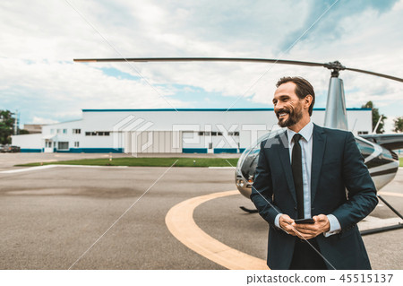 Handsome man smiling while standing on the helicopter platform Handsome man smiling while standing on the helicopter platform 45515137