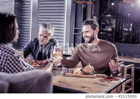 Positive delighted young man touching bocals with partners Positive delighted young man touching bocals with partners 45515930