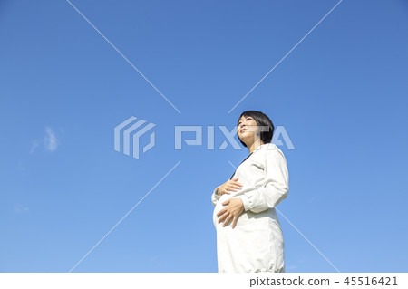 在上個月的一名孕婦的狀態用她的手希望到大肚子對藍天背景。懷孕，上個月，愛，有趣，快樂的形象 45516421