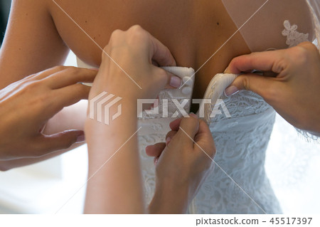 Hands of girlfriends helping the bride to dress her dress Hands of girlfriends helping the bride to dress her dress 45517397