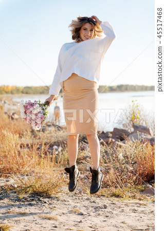 Pregnant woman happily jumping with the bunch of flowers 45517468