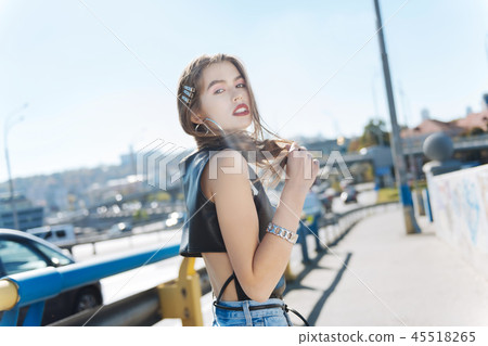 Dark-haired model with red lips wearing short black leather top 45518265
