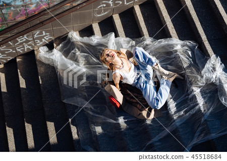 Model wearing white shirt and baggy jeans sitting on the stairs Model wearing white shirt and baggy jeans sitting on the stairs 45518684