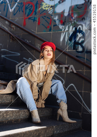 Young skinny model wearing jeans and high-heeled boots sitting on stairs 45519158