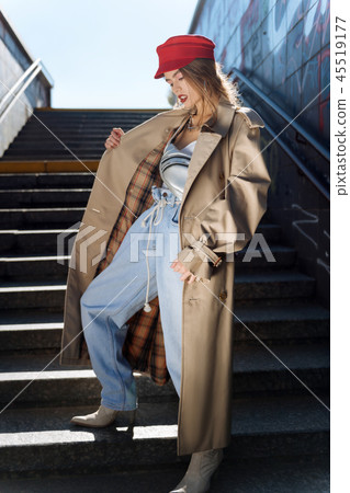 Slim dark-haired model wearing baggy jeans and beige trench coat Slim dark-haired model wearing baggy jeans and beige trench coat 45519177