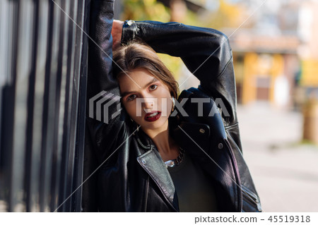 Stylish dark-eyed fashion model posing in oversize leather jacket 45519318