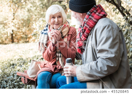 Joyful nice woman holding a cup with hot tea Joyful nice woman holding a cup with hot tea 45520845