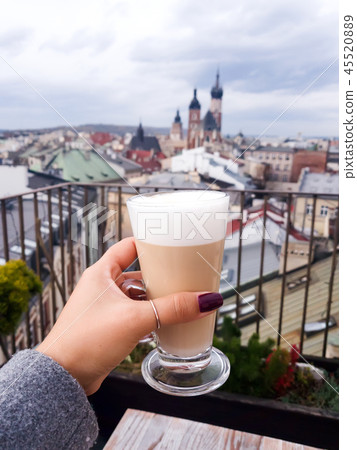 Woman holding coffee cup in cafe on a roof with view to St. Mary's Church Krakow , Poland at the 45520889