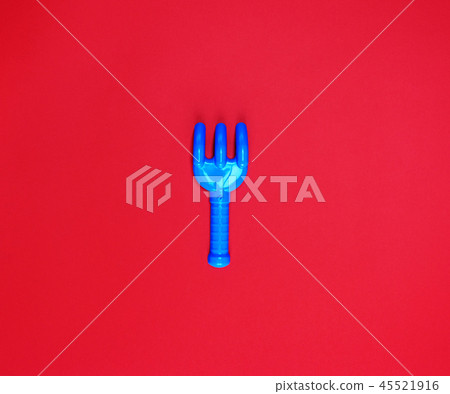 blue plastic baby rake on a red background 45521916