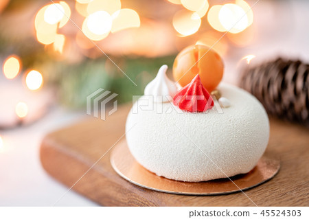 Mini mousse pastry dessert covered with white velour on garland lamps bokeh background. Modern Mini mousse pastry dessert covered with white velour on garland lamps bokeh background. Modern 45524303