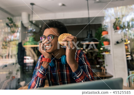 Happy delighted man eating a tasty cookie Happy delighted man eating a tasty cookie 45525585