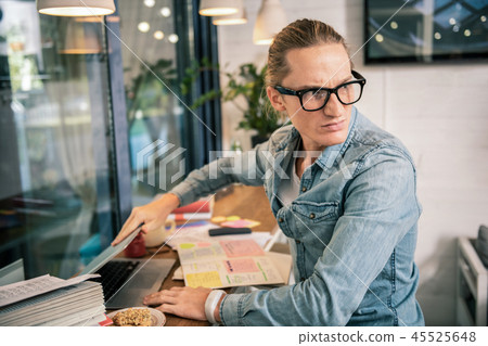 Unhappy cheerless young man closing his laptop Unhappy cheerless young man closing his laptop 45525648