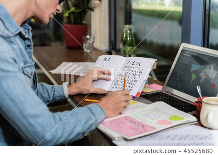 Pleasant young man doing his homework Pleasant young man doing his homework 45525680