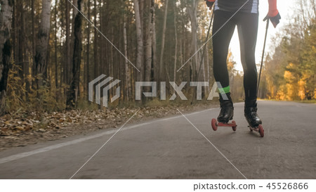 Training an athlete on the roller skaters. Biathlon ride on the roller skis with ski poles, in the Training an athlete on the roller skaters. Biathlon ride on the roller skis with ski poles, in the 45526866
