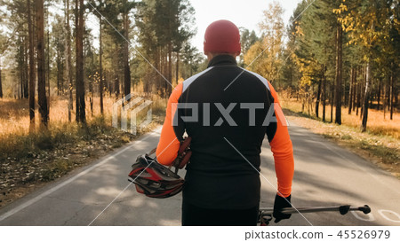 Training an athlete on the roller skaters. Biathlon ride on the roller skis with ski poles, in the Training an athlete on the roller skaters. Biathlon ride on the roller skis with ski poles, in the 45526979