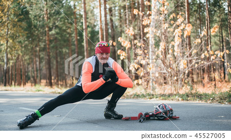 Training an athlete on the roller skaters. Biathlon ride on the roller skis with ski poles, in the Training an athlete on the roller skaters. Biathlon ride on the roller skis with ski poles, in the 45527005