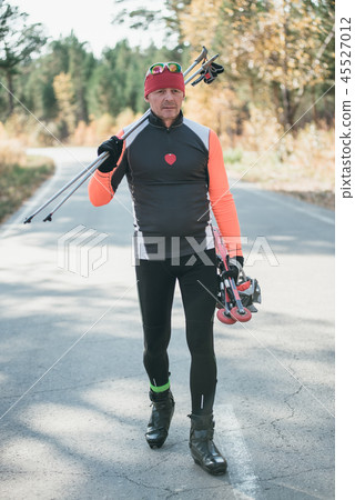 Training an athlete on the roller skaters. Biathlon ride on the roller skis with ski poles, in the Training an athlete on the roller skaters. Biathlon ride on the roller skis with ski poles, in the 45527012