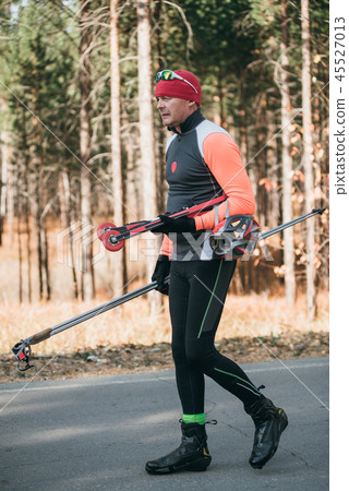 Training an athlete on the roller skaters. Biathlon ride on the roller skis with ski poles, in the Training an athlete on the roller skaters. Biathlon ride on the roller skis with ski poles, in the 45527013