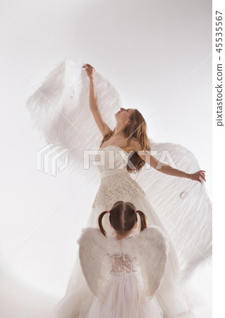 a woman and a girl in white dresses with angel a woman and a girl in white dresses with angel 45535567