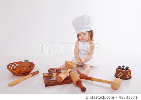 a little girl in a chef's hat and an apron sitting a little girl in a chef's hat and an apron sitting 45535571