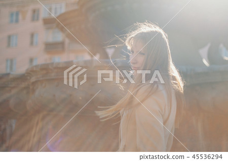 girl walking in a coat, the wind waving her hair 45536294