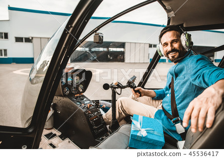 Bearded pilot smiling and looking at you from helicopter cabin Bearded pilot smiling and looking at you from helicopter cabin 45536417