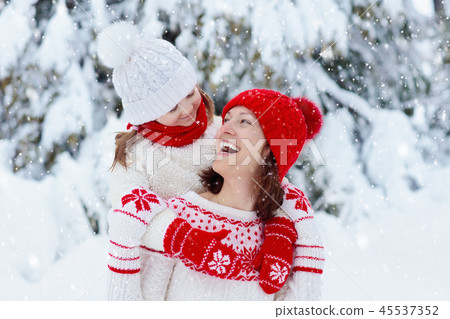 Mother and child in knitted winter hats in snow. 45537352