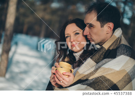man and woman wrapped inblanket holding cups 45537388