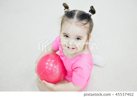 a little girl in a pink swimsuit with a small ball a little girl in a pink swimsuit with a small ball 45537402