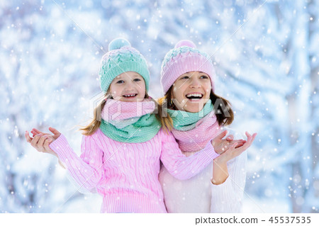 Mother and child in knitted winter hats in snow. 45537535