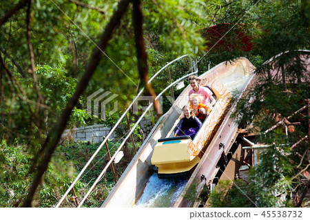 Family with kids on roller coaster in theme park. 45538732