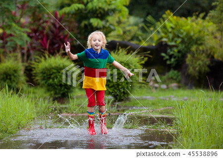 Kid with umbrella playing in summer rain. Kid with umbrella playing in summer rain. 45538896