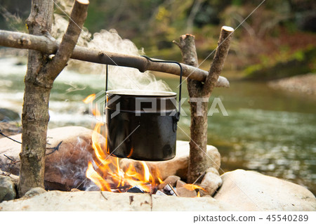 Cooking food in pot over campfire outdoor 45540289