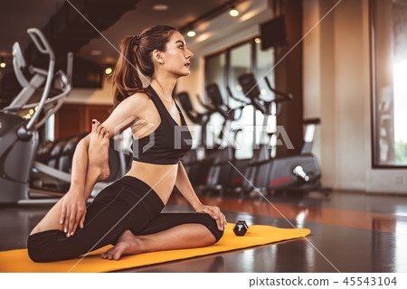 Woman doing bending legs yoga in fitness workouts training gym c Woman doing bending legs yoga in fitness workouts training gym c 45543104