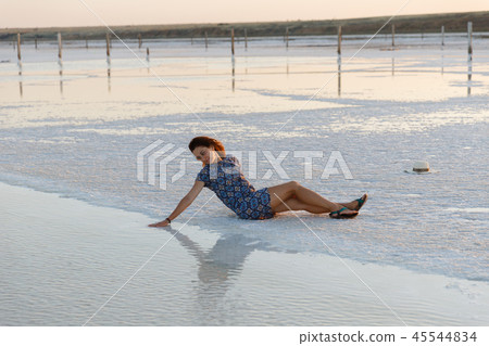 happy girl enjoying the sunset, touches water of a salt lake sitting on crystals happy girl enjoying the sunset, touches water of a salt lake sitting on crystals 45544834
