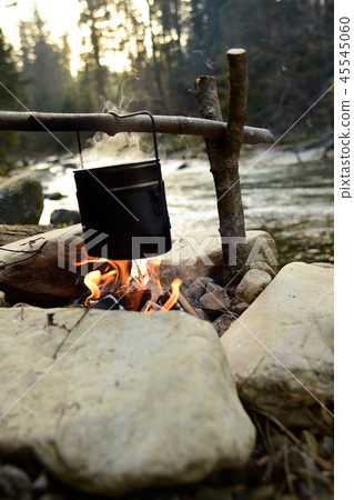 Cooking food in pot over campfire outdoor 45545060